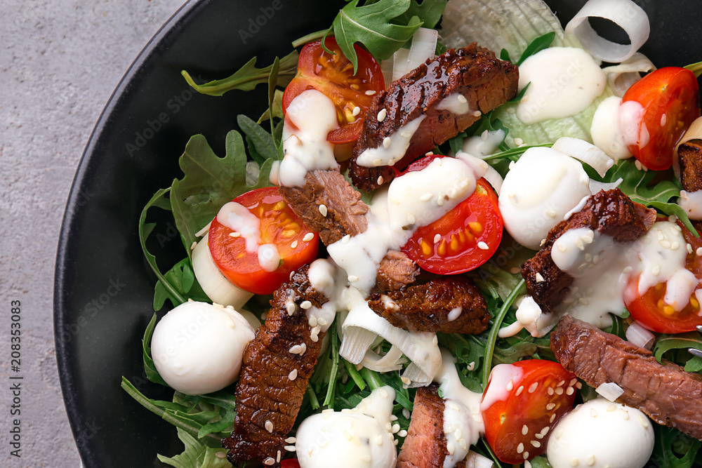 Tasty salad with meat, cherry tomatoes and mozzarella on plate