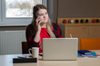 © ako-photography - A blonde woman sitting at a laptop and talking over a cell phone.