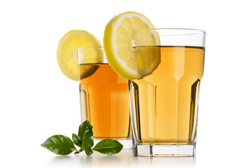 Wall Mural - two glasses full of ice tea with lemon slices and tea leaves on white background