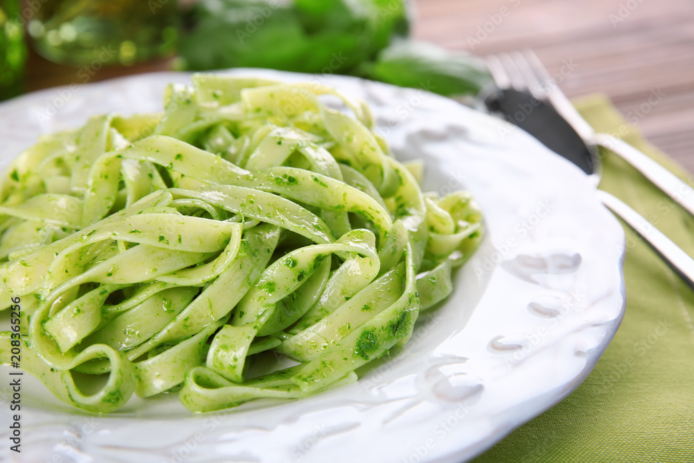 Plate of delicious pasta with pesto sauce on table