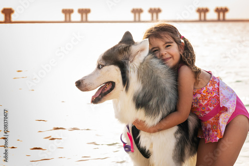 Little Girl Hugs Husky Dog At The Beach In Dubai Buy This