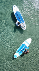 Aerial drone bird's eye view of a man exercising sup board in turquoise tropical clear waters at sunset