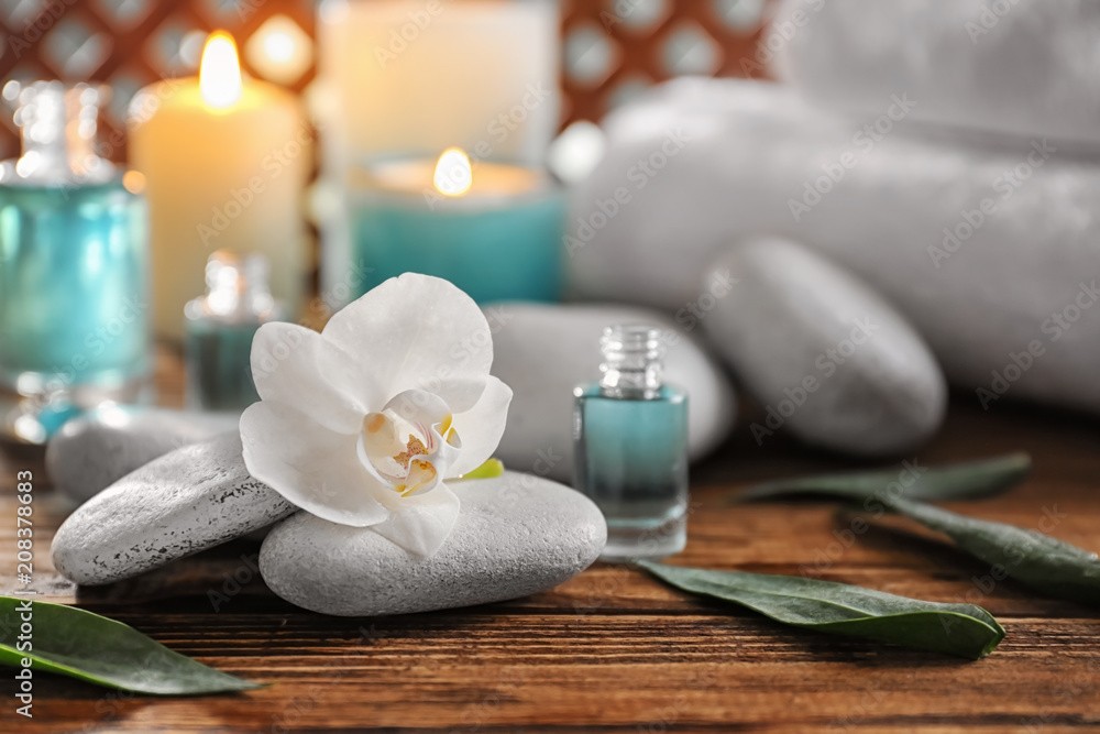 Spa stones with beautiful flower on wooden table
