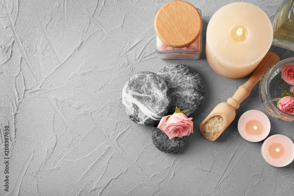 Spa composition with candles and stones on grey background, top view