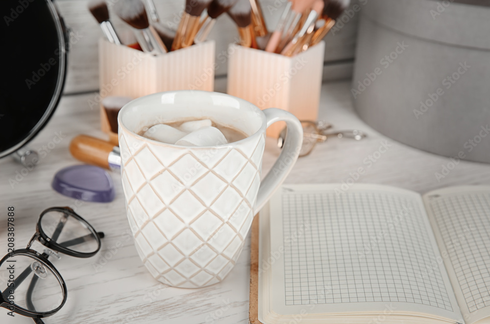 Cup of coffee, notebook and decorative cosmetics on table