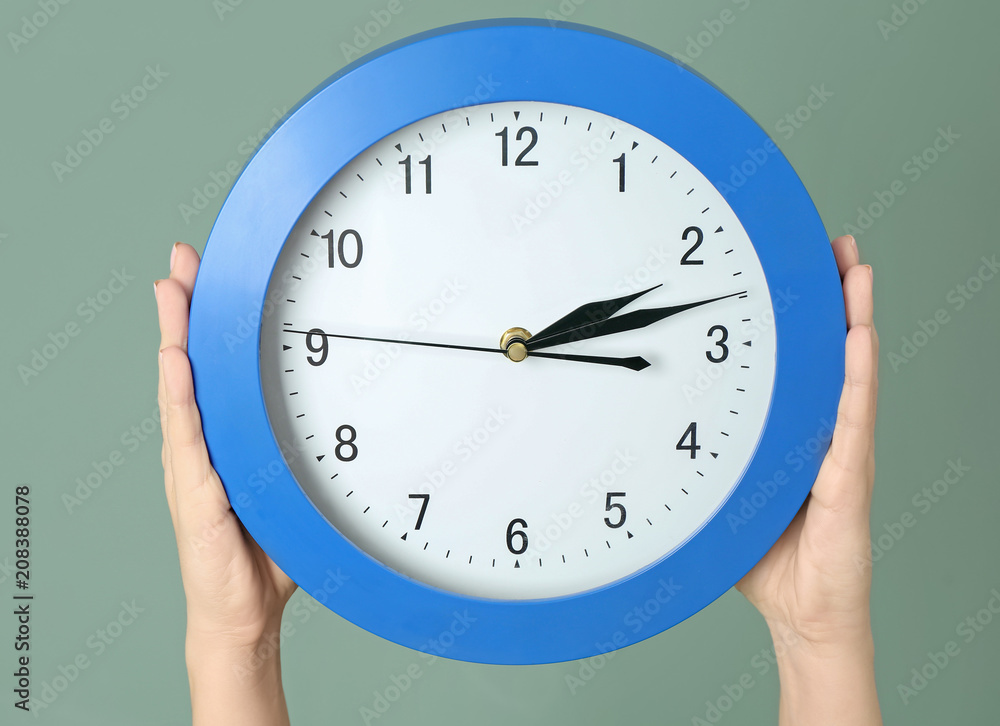 Woman holding clock on color background. Time management concept