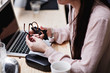 © Maskot - Midsection of businesswoman cleaning eyeglasses by laptop at table in office