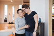 © Maskot - Happy lesbian couple standing in living room at home