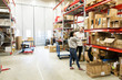 © Maskot - Coworkers examining while standing at warehouse