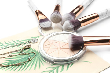 Decorative cosmetic, brushes and necklaces on white background, closeup