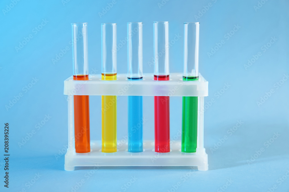 Test tubes with colorful liquids in holder on color background