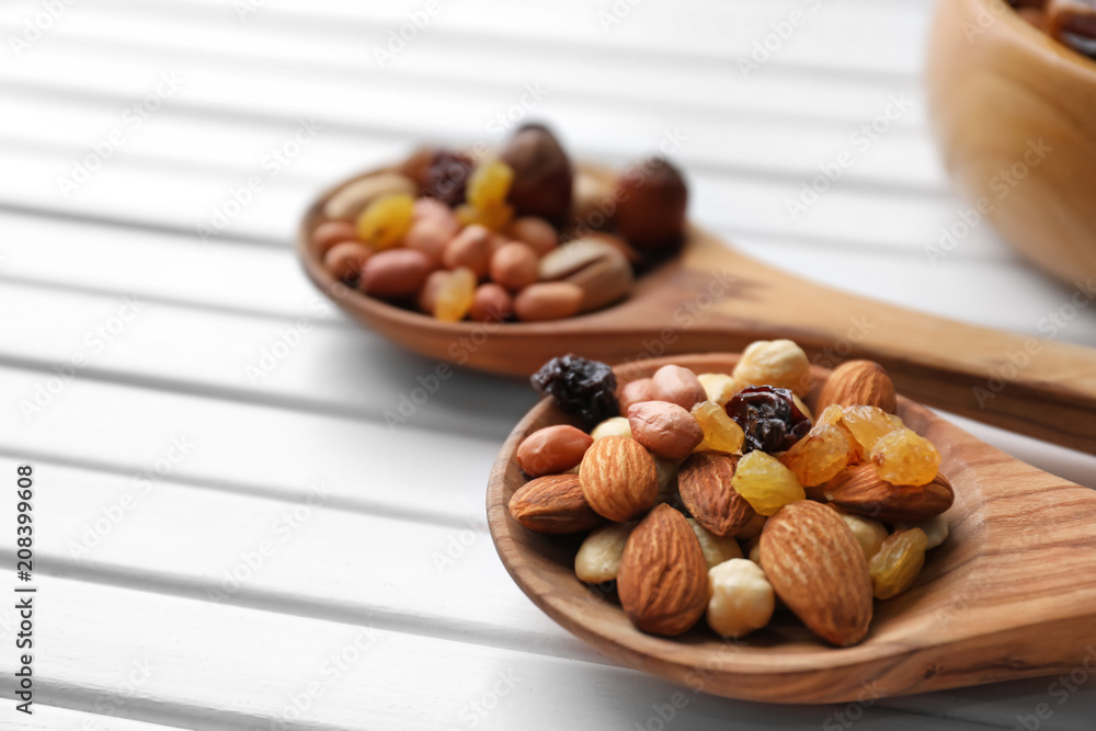 Spoons with different nuts and raisins on wooden table