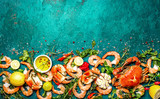 Fresh raw seafood - shrimps and crabs with herbs and spices on turquoise background. Copy space