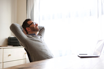 Wall Mural - man relaxing with hands behind head in front of laptop