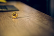 © Svyatoslav Lypynskyy - Single bitcoin on table. Picture of one golden bitcoin standing in equilibrium on light brown wooden desk with laptop in background.