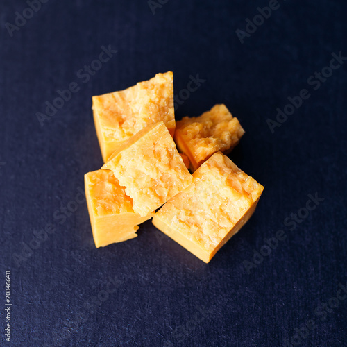 Fotografia Cheese in peaces on the black background square