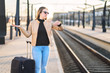 © terovesalainen - Train late, delayed, canceled or behind schedule. Confused woman looking at the time and watch while waiting in platform.  Unhappy person spreading hands.