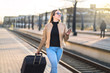 © terovesalainen - Confident business woman pulling suitcase and holding mobile phone in train station. Smiling lady walking in platform and using smartphone. Female traveler arrived to destination.