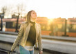 © terovesalainen - Happy woman walking in platform after arriving to destination in train station. Smiling female traveler with suitcase in sunset. Freedom and wanderlust.