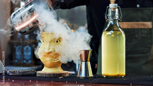 Cuadros en Lienzo The bartender pours steam in a Tiki glass