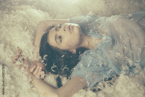 Fotografía Dreamy girl lying on downy heap of white feathers