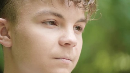 Wall Mural - Close up emotional portrait of caucasian smiling teen boy. Handsome guy. Funny cute teenager in summer park at day. Child looking away.