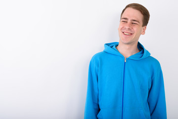 Wall Mural - Young handsome man wearing blue hoodie against white background