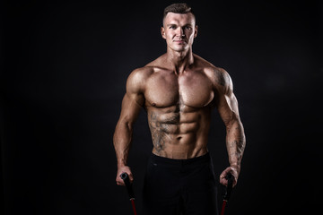 Wall Mural - Handsome muscular strong man doing pulling exercise and working hard isolated on dark background