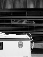Weißes Wohnmobil Vor Moderner Dunkler Fassade Am Antonipark Am Hafen In Hamburg St. Pauli, Fotografiert In Klassischem Schwarzweiß