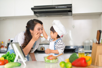 Wall Mural - Mother with her daughter in the kitchen cooking together