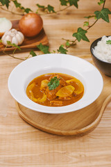 Wall Mural - Tasty dinner with chicken curry in bowl on wooden background