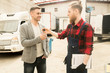 © Seventyfour - Young bearded auto mechanic giving car keys to happy male client after successful inspection of his vehicle in service garage