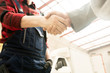 © Seventyfour - Low angle view of unrecognizable male auto technician in workwear shaking hands with car owner in service garage