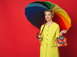 © Prostock-studio - Happy girl in yellow coat posing at red background