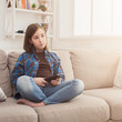 © Prostock-studio - Young serious girl watching TV with remote control