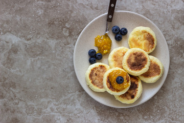 Cottage cheese pancakes (syrniki) with sour cream, orange jam and fresh blueberries on a plate. Breakfast or lunch concept. 