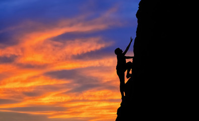 black silhouette people climb the cliff.