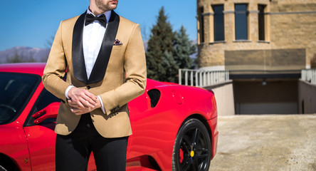 Wall Mural - Man in custom tailored tuxedo, suit posing outdoors in front of expensive car