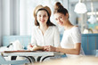 © pressmaster - Two friendly students sitting in cafe, looking at you, reading book and preparing home assignment