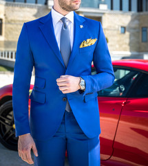 Wall Mural - Man in expensive custom tailored suit posing in front of expensive car outdoors