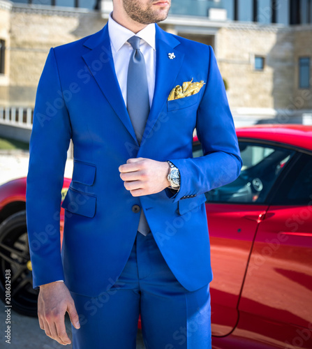 Man in expensive custom tailored suit posing in front of expensive car outdoors Wallpaper Mural