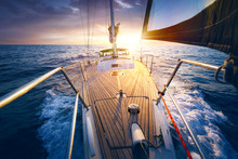 Sunset At The Sailboat Deck While Cruising / Sailing At Opened Sea. Yacht With Full Sails Up At The End Of Windy Day. Sailing Theme - Background. Yachting Design.