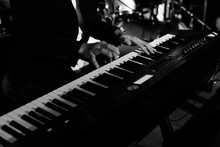 A Pianist Musician Is Performing And Playing Some Nice Music By Using A Piano Keyboard On A Stage At Some Nightclub Or Pub With His Band. Black And White Photo