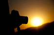 © emrekaya - Photographer taking pictures outdoors, silhouette of a man with camera over sunset background