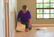 © Michael O'Keene - DIY homeowner man or professional maintenance and installer installing new tan vinyl tile flooring square panels in someone's home during reconstruction and remodeling.