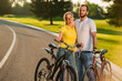 © DenisProduction.com - Loving couple enjoying sunny day on bikes. Young people in love standing with bicycles on the road and looking at camera. Romantic holidays concept.