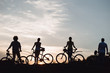 © DenisProduction.com - Four young cyclists at beautiful sunset. Silhouettes of young people with bicycles at amazing sunset. Enjoying the nature.