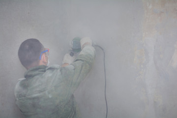 Professionality male contractor using professional angle grinder for cutting wall