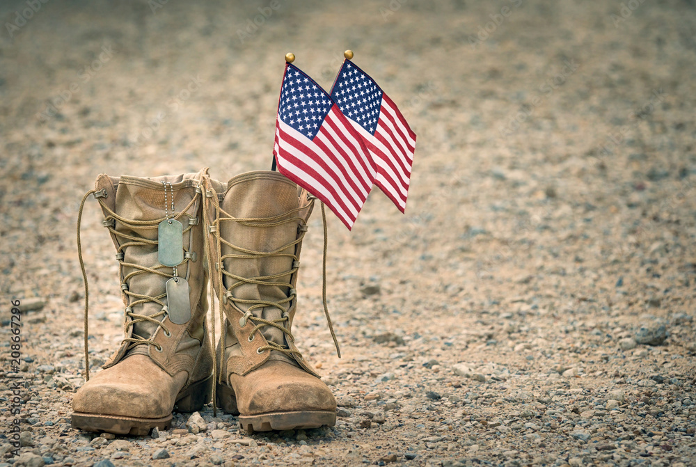 Old military combat boots with dog tags and two small American flags. Rocky gravel background with copy space. Memorial Day or Veterans day concept. - obrazy, fototapety, plakaty 