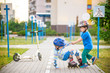 two boys in park, help boy with roller skates to stand up